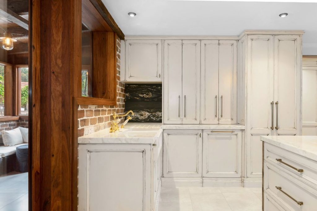 White cabinet kitchen with wall cut out into living room