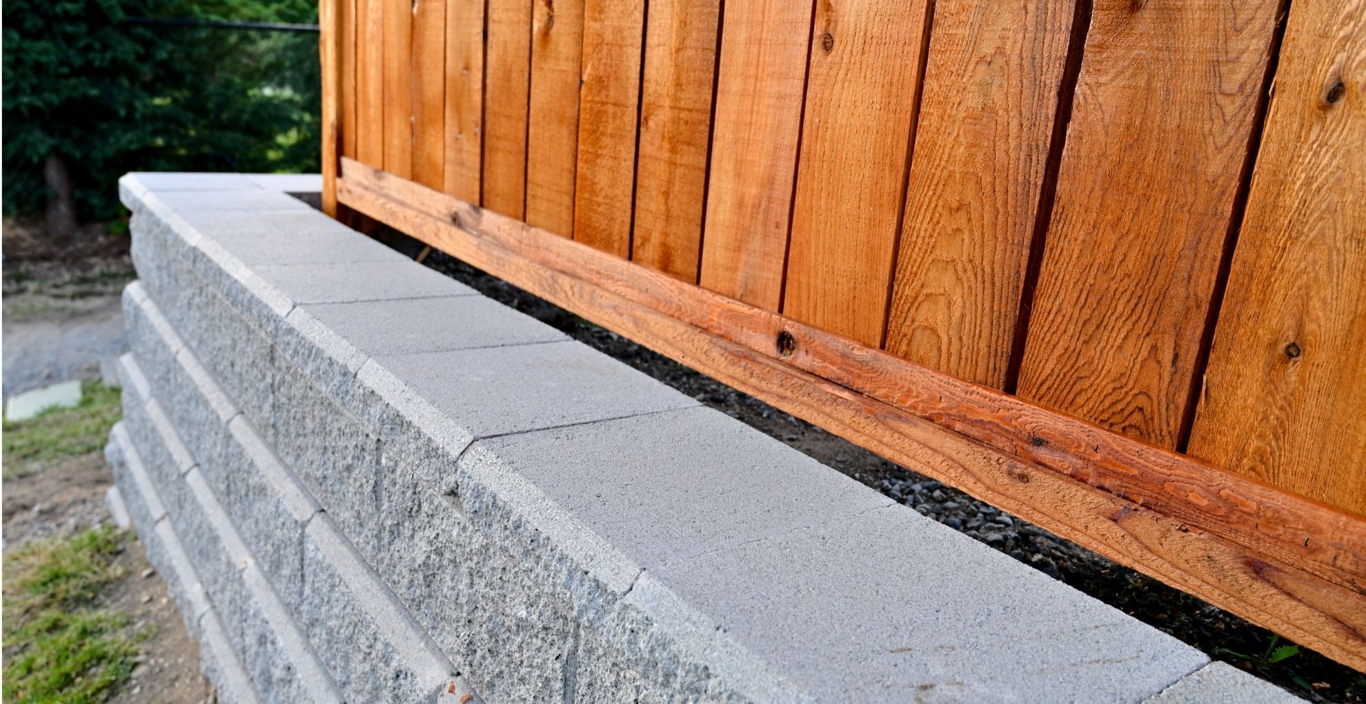 showing a retaining wall underneath a fence to support drainage